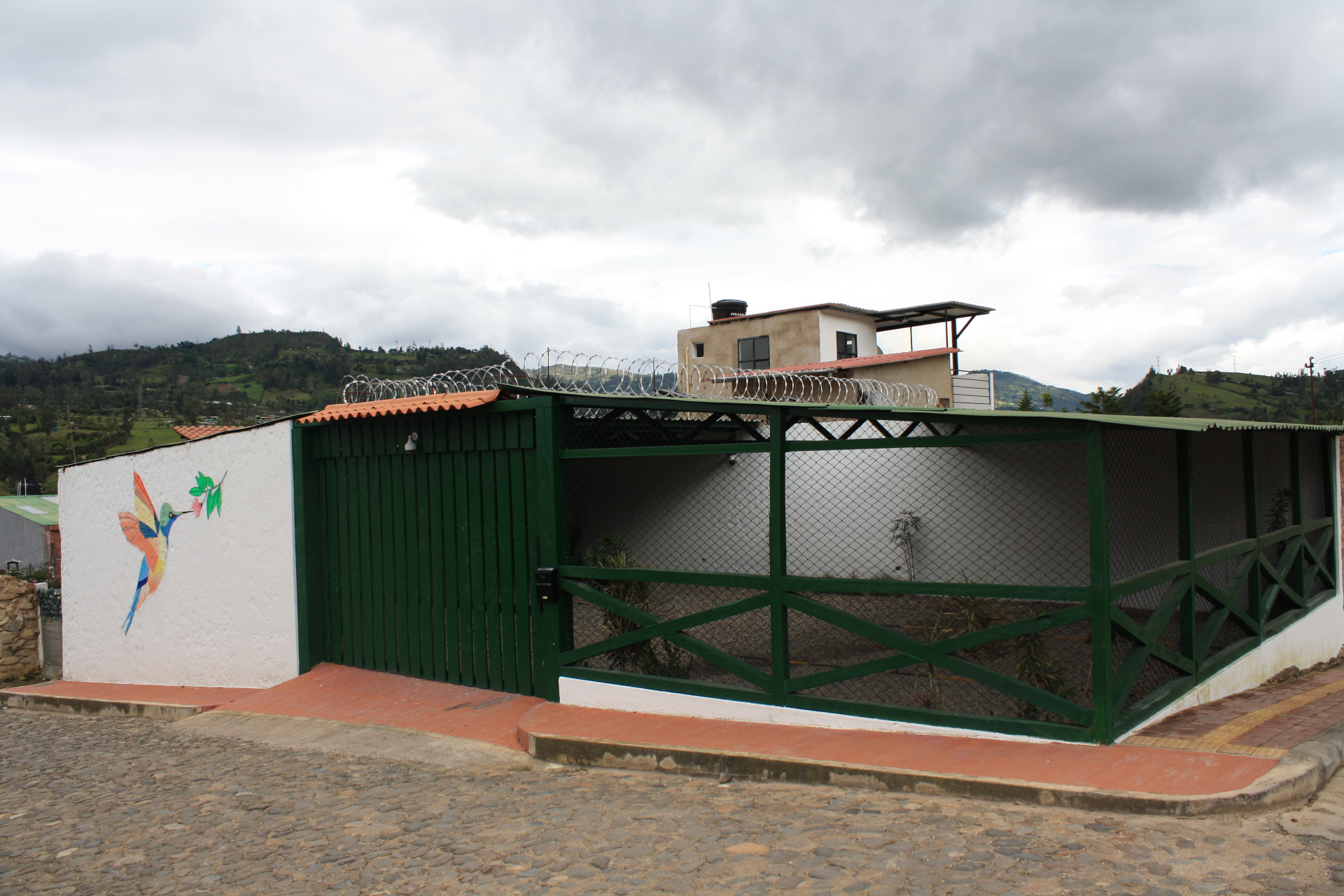 Fachada del Hotel Santino con parqueadero privado techado y mural de colibrí — Jenesano, Boyacá