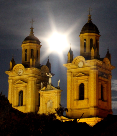 Iglesia colonial de Jenesano iluminada de noche con la luna entre sus torres