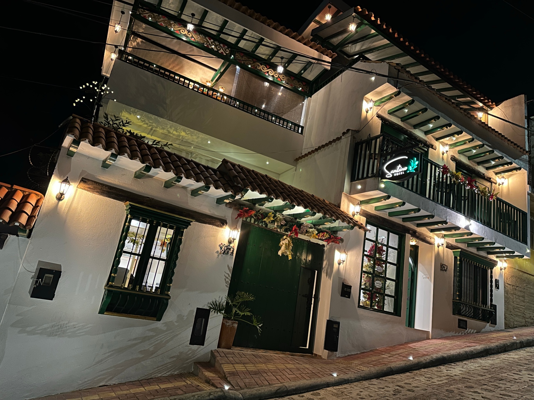 Hotel Santino iluminado de noche en Jenesano con balcones y fachada colonial contemporánea