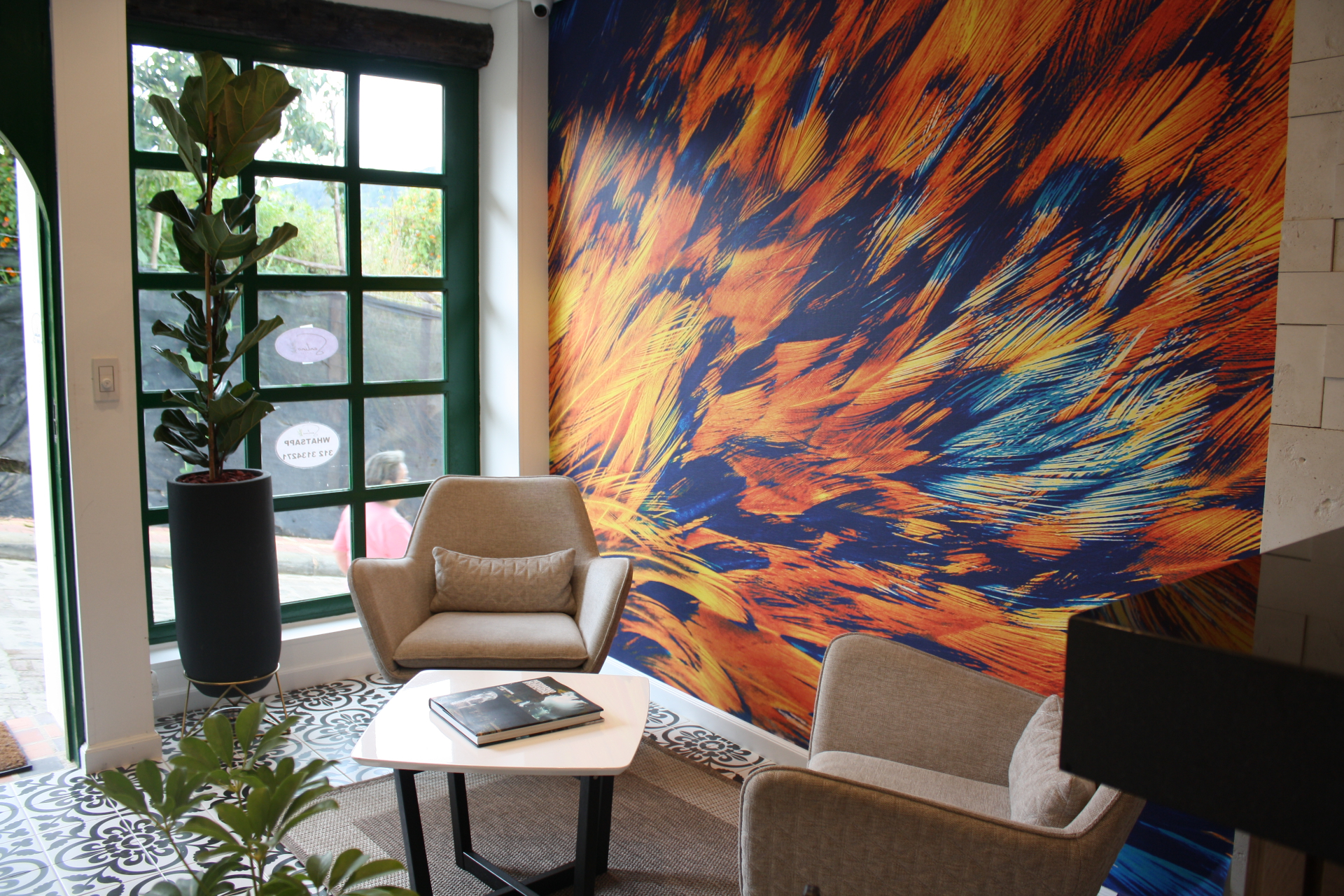 Sala de espera del Hotel Santino con mural de plumas y sillas tapizadas