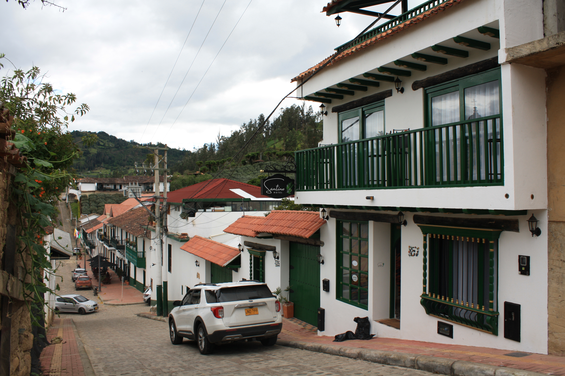 Fachada del Hotel Santino con parqueadero techado y acceso principal sobre calle empedrada