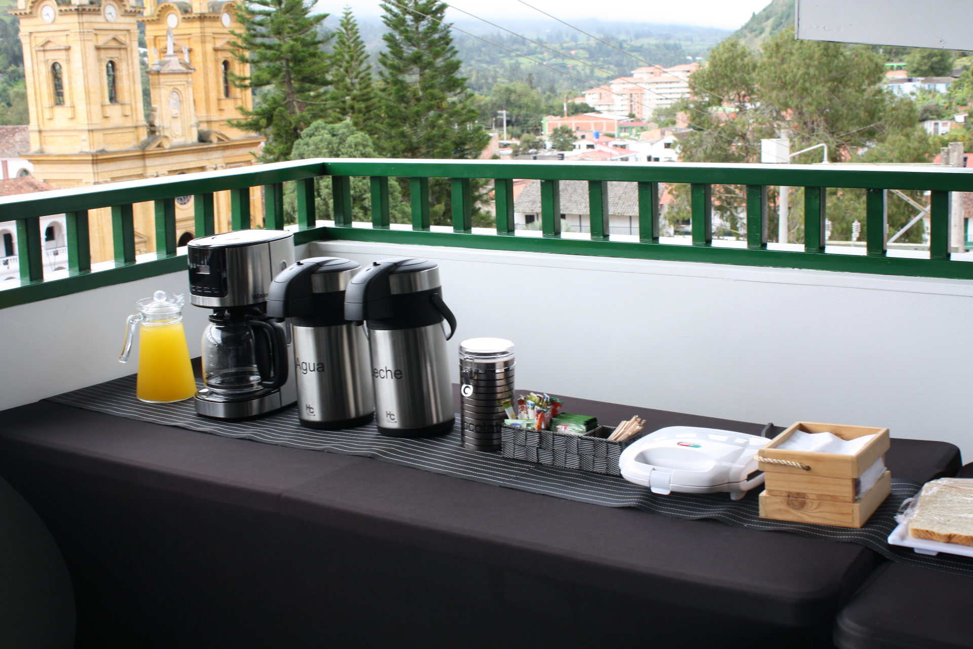 Estación de café y bebidas en terraza del Hotel Santino con vista a la iglesia de Jenesano