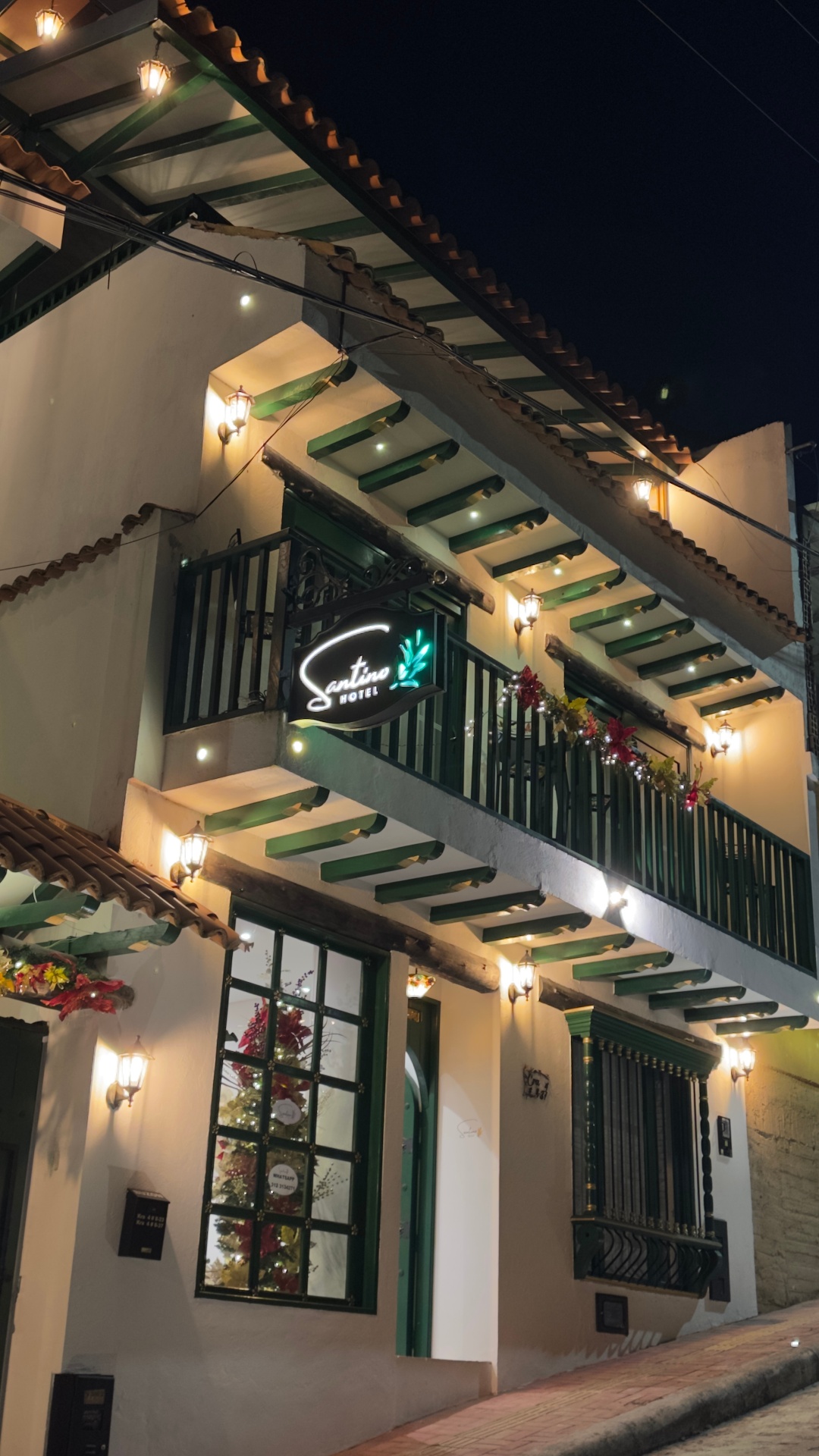 Fachada vertical del Hotel Santino iluminada en la noche desde la calle inclinada