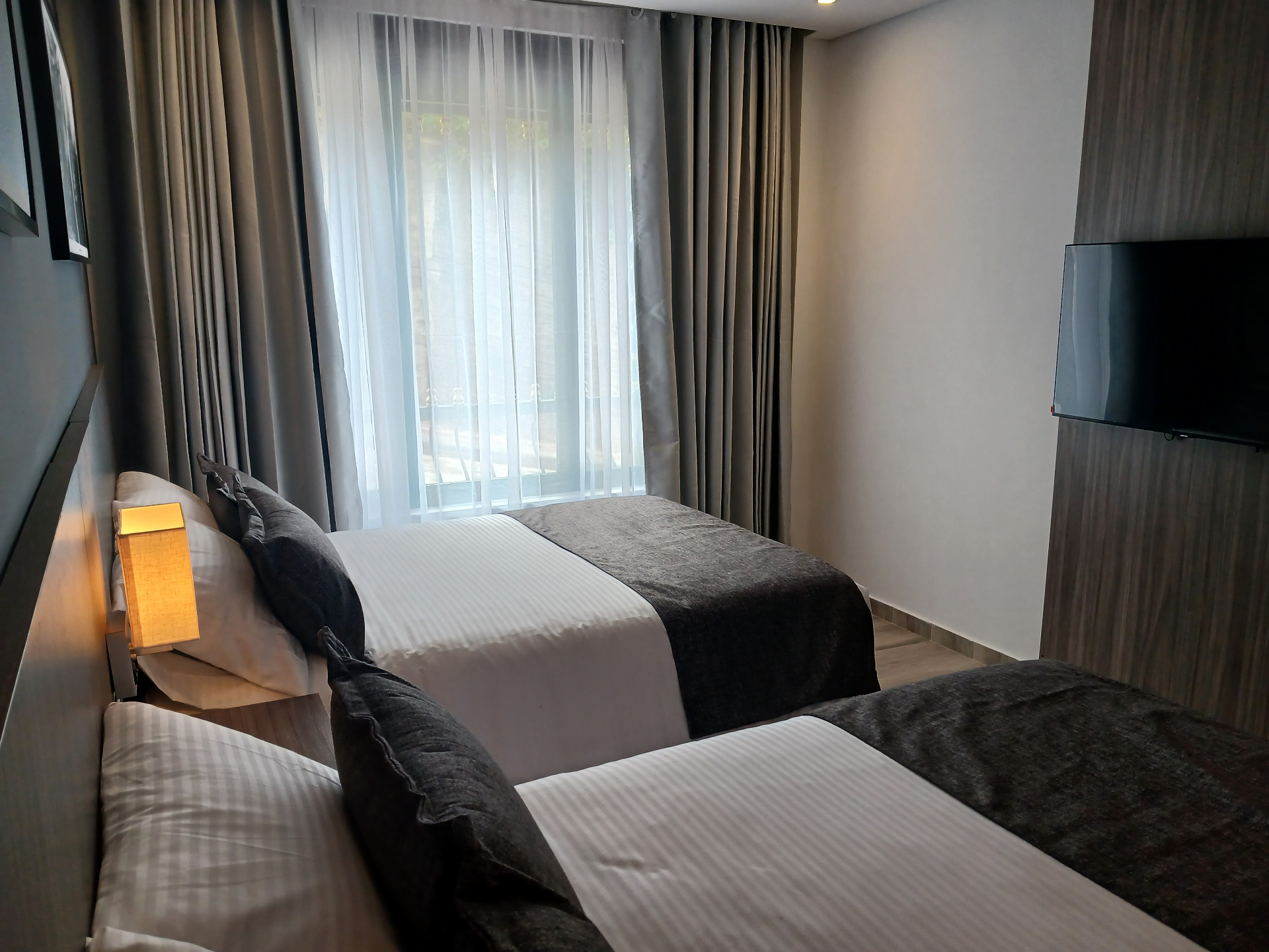 Smart TV y zona de descanso dentro de la habitación cuádruple del Hotel Santino