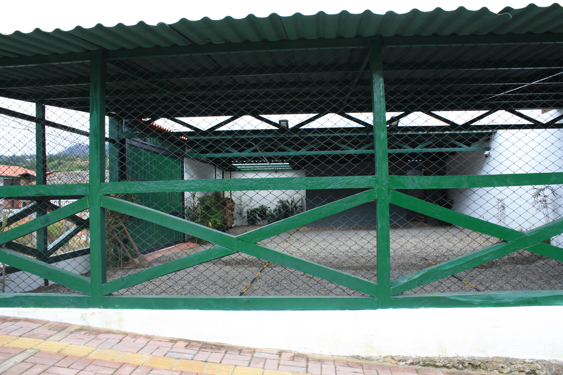 Vista interior del parqueadero cubierto del Hotel Santino con estructura verde