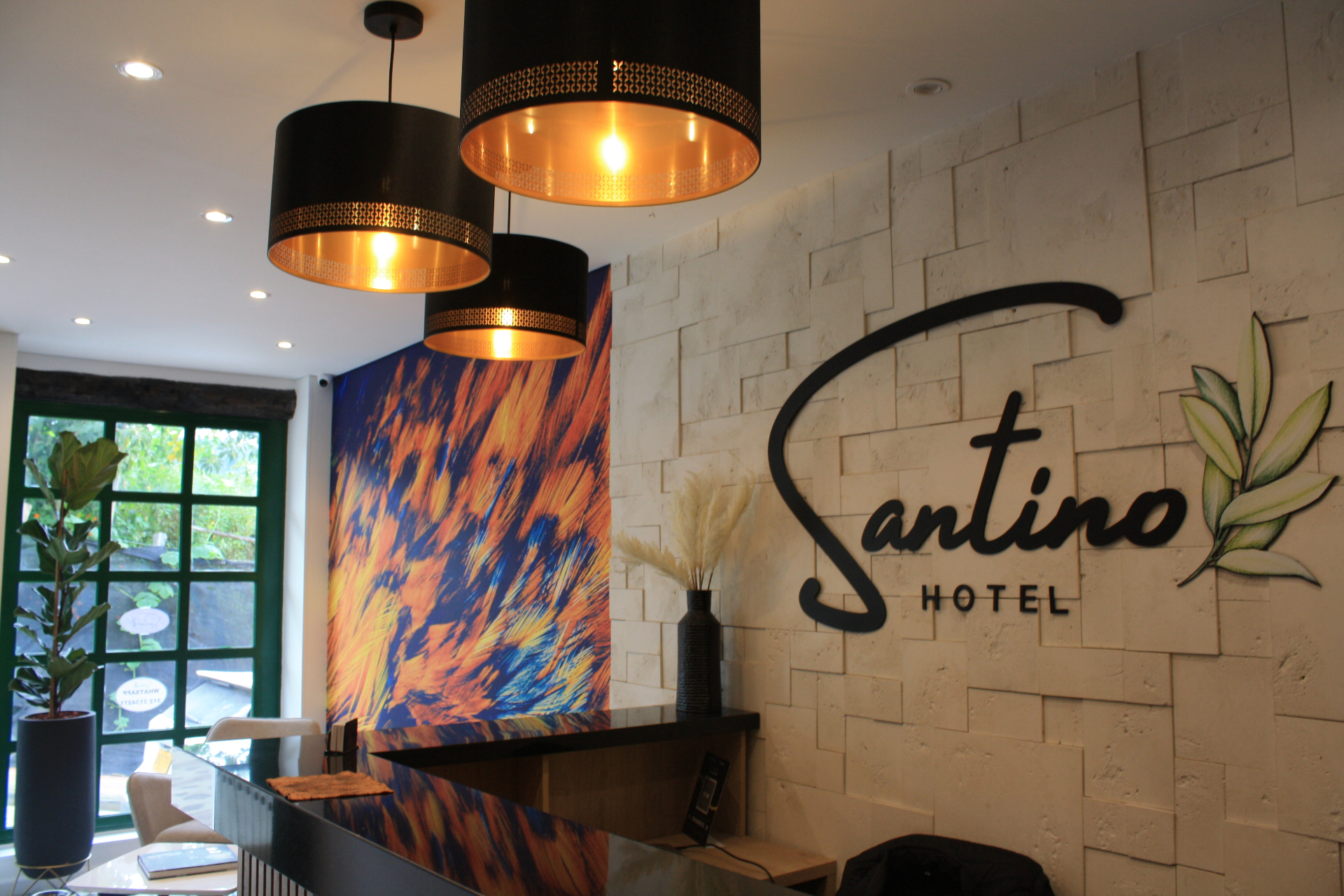 Recepción del Hotel Santino con logo en gran formato y lámparas cálidas